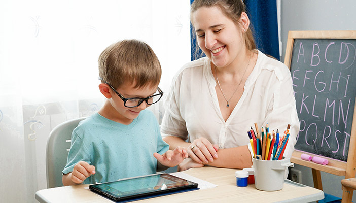 Three smiling children grouped around a laptop