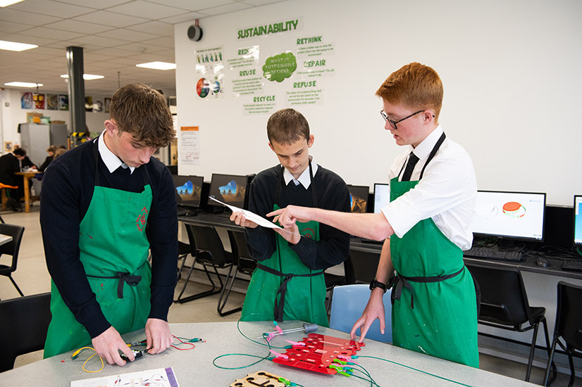 Three school pupils in a science class working with circuits.